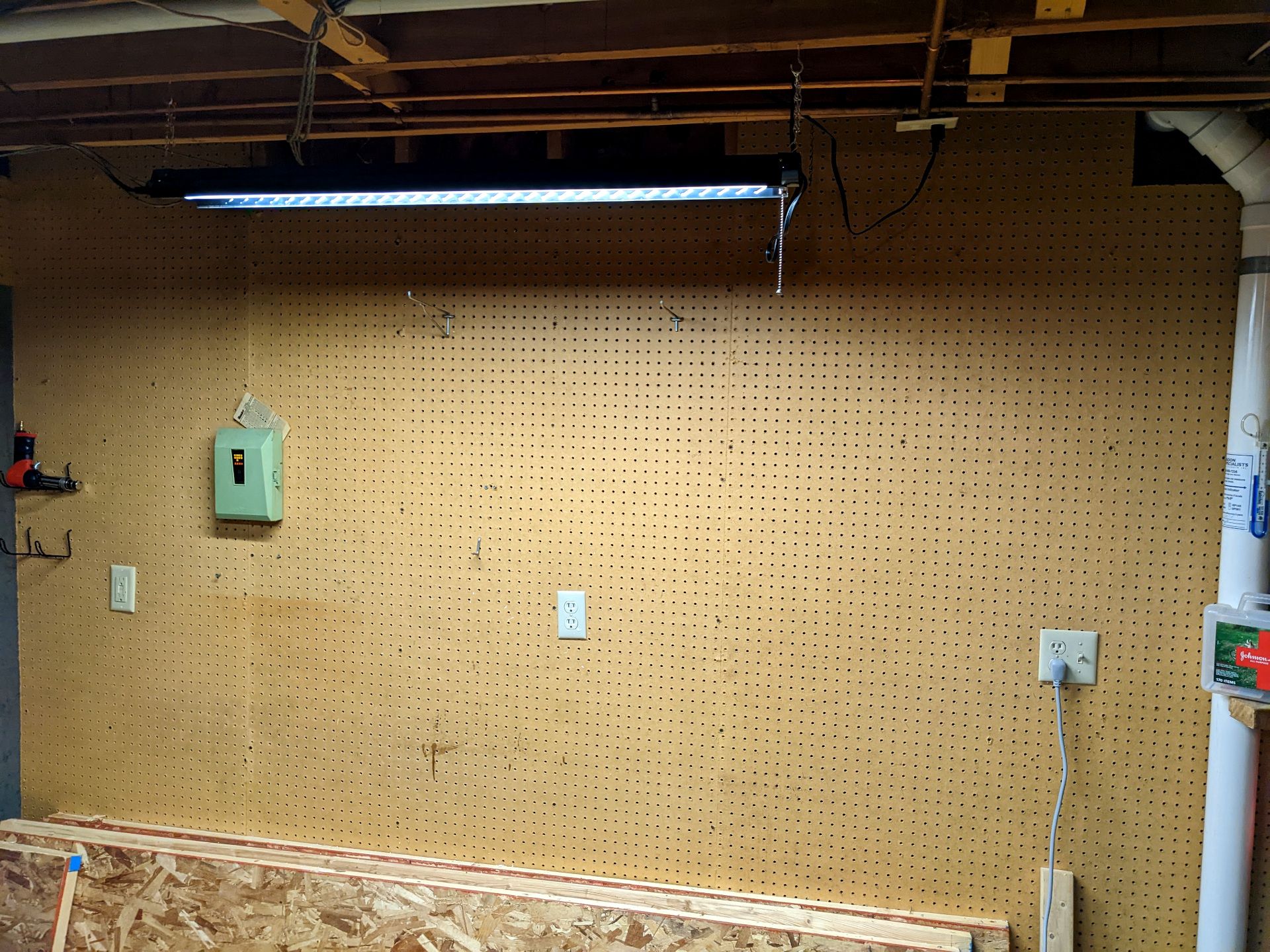 An empty pegboard, save one rivet gun on the far left