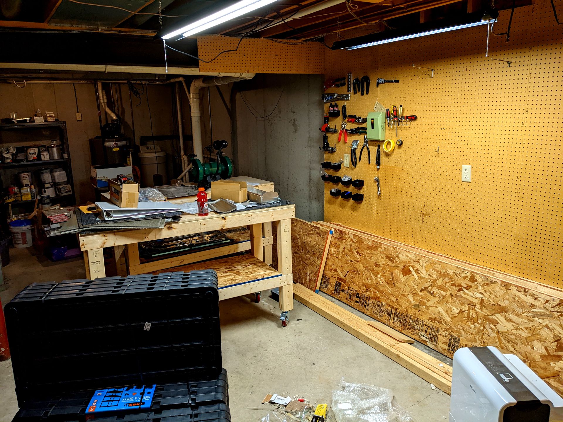 A zoomed out shot of the workshop. Tools are hung on the pegboard but the rest is a mess