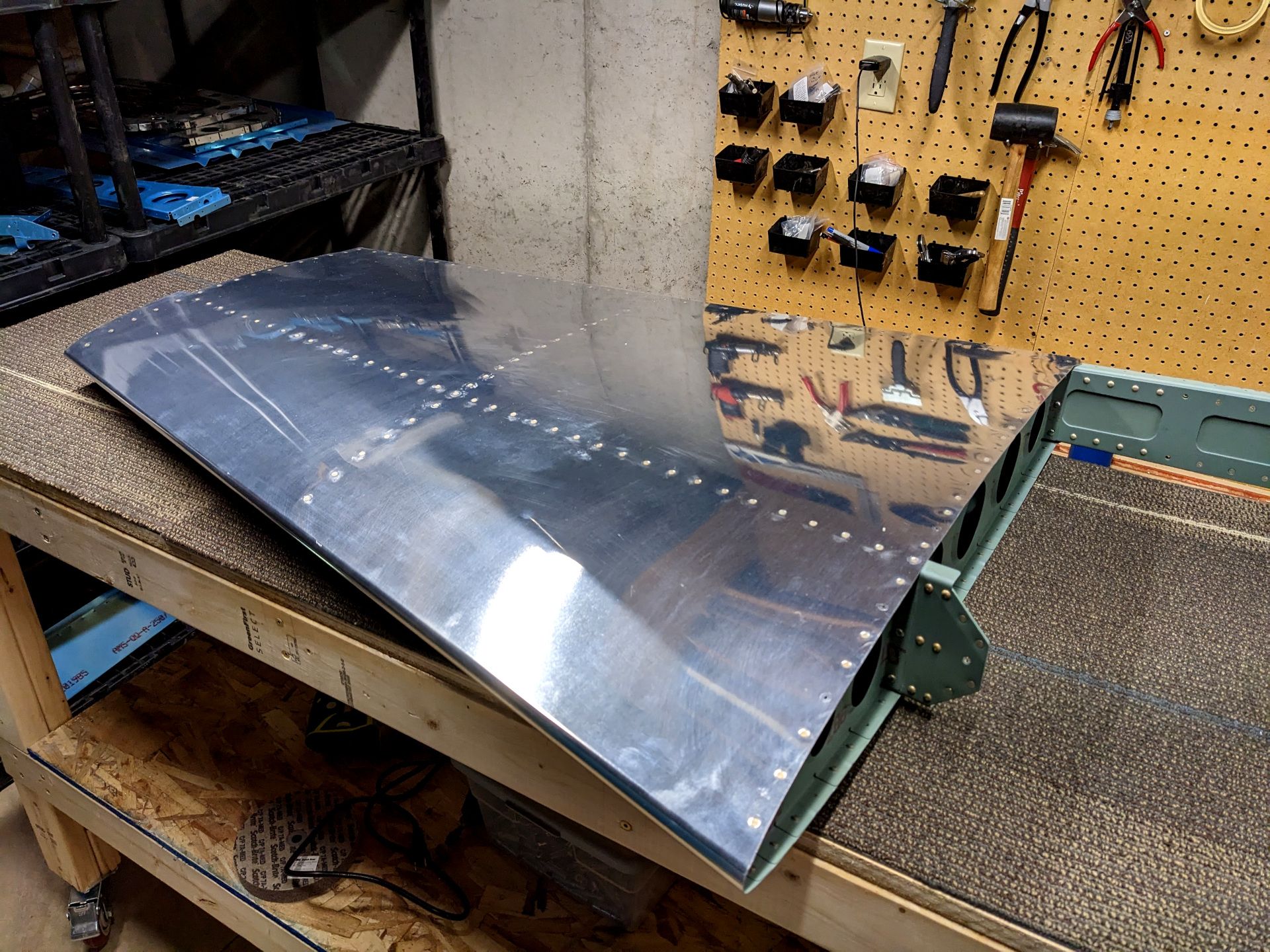 Vertical stabilizer for an airplane sitting on a workbench. The aluminum is bare.
